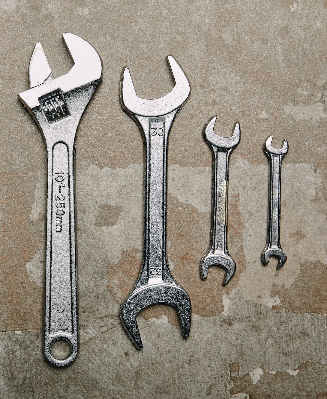 Top view of set of wrenches tools and one monkey wrench on the background of old surface