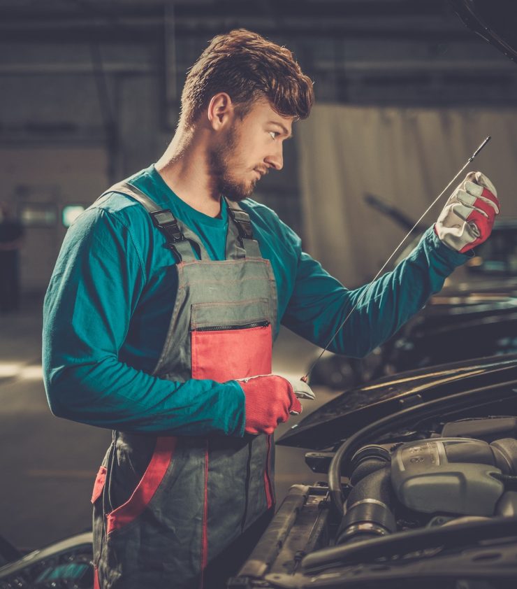 Mechanic checking oil level in a car workshop