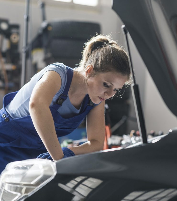 Professional female mechanic repairing a car